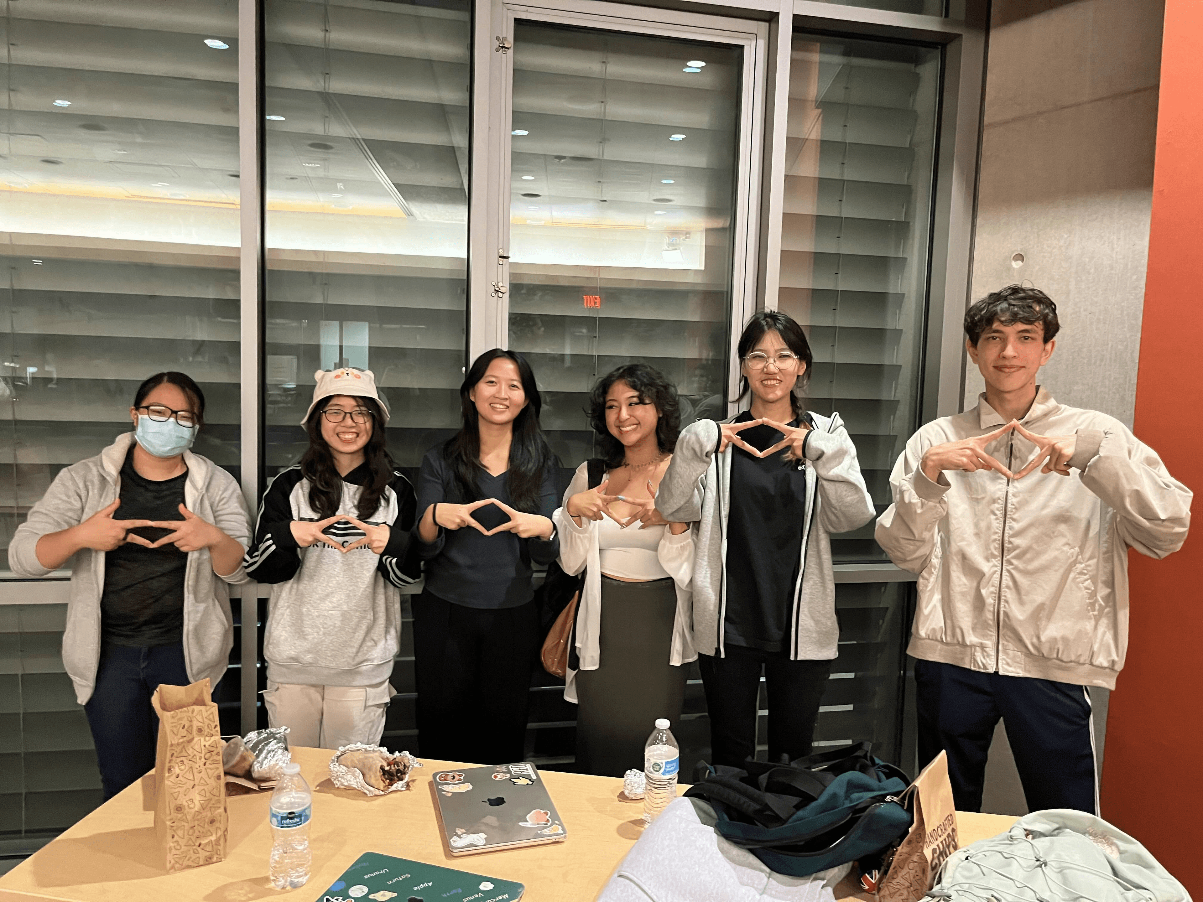 a project team makes diamond signs with their hands at project showcase, celebrating the completion of their project over the course of a quarter